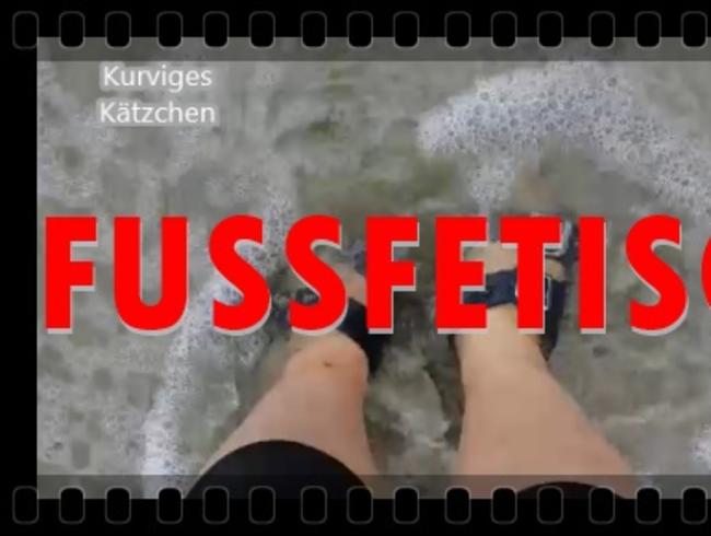 Kleine Füße in Sandalen im Meer