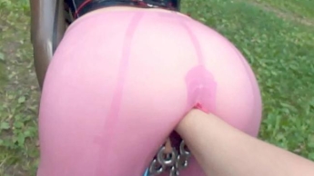 Latexpuppe in rosa Leggings mit Piercing im Freien gefistet