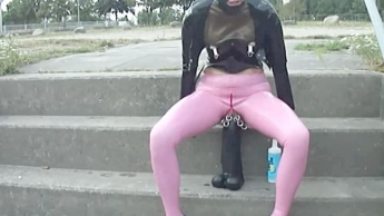 Latexpuppe in rosa Leggings und Korsett fickt einen riesigen Monsterdildo und pisst in der Öffentlichkeit