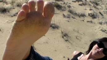 Rot lackierte Zehen im Strandsand
