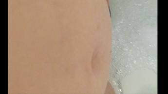 Schwangeres Mädchen mit behaarter Muschi zeigt ihren Bauch in der Dusche und pinkelt ein bisschen in der Badewanne