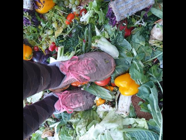 Uaerwunsch mit Sportschuhen auf dem Misthaufen Obst und Gemüse zertrampeln